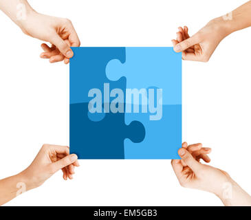 four hands connecting puzzle pieces Stock Photo