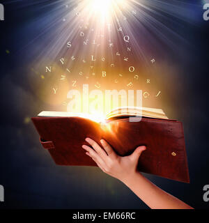 Human hand holding magic book with magic lights Stock Photo