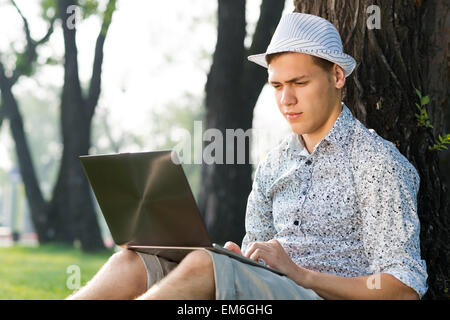 young man working in the park with a laptop Stock Photo