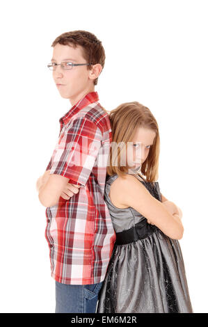A tall brother and small sister standing back to back isolated for white background and are mad to each other. Stock Photo