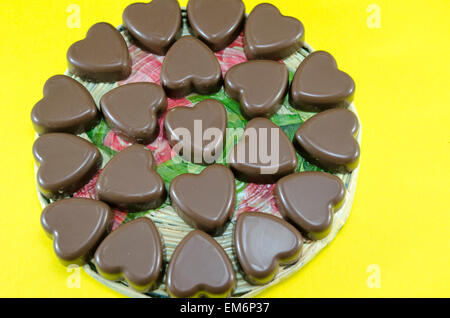 Deliciously looking heart shaped chocolate on yellow background Stock Photo