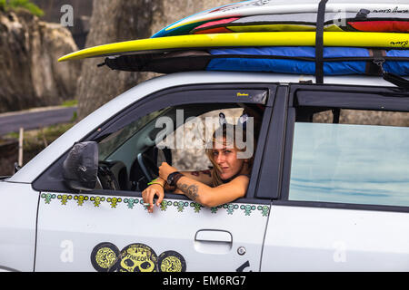 Teenage girl sitting in car with surfboard. Stock Photo