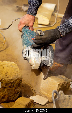Construction worker on building site using circular saw to cut stone into shape Stock Photo