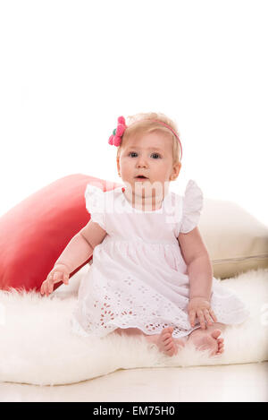 Beauty blond baby girl with headband with flower sitting on fluffy blanket Stock Photo