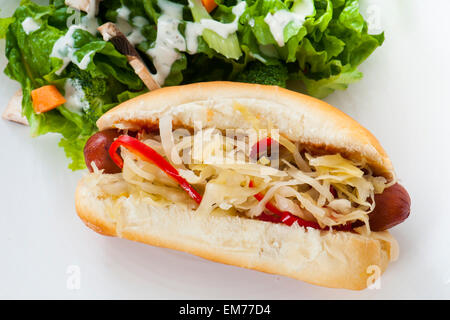 Grilled Hot Dog with sauerkraut and hot red peppers, with side salad Stock Photo