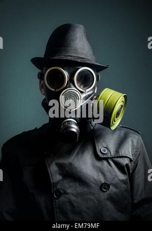 Man in gas mask, raincoat and black hat at dark background Stock Photo