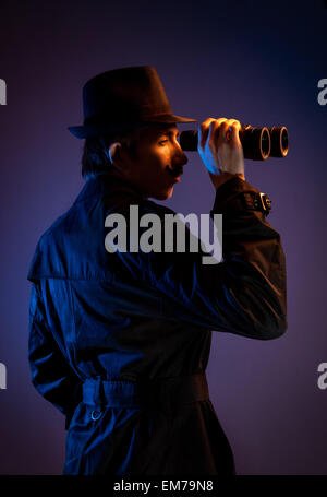 Man in black hat with binocular spying for somebody at dark background Stock Photo