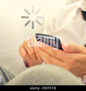 young man using a smartphone and a loading sign Stock Photo