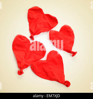 some deflated heart-shaped balloons on a beige background, with a retro effect Stock Photo