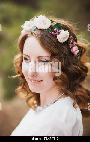 beautiful woman portrait.  flower wreath in hair of bride. smiley female face. close up of young girl outside. Stock Photo