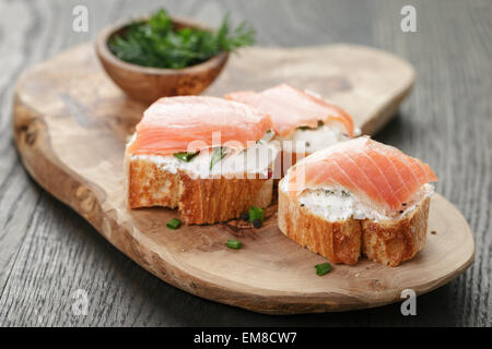 baguette slices with smoked salmon and cheese cream on wooden table Stock Photo