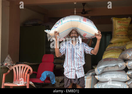 A man carrying a heavy bag of rice on his head in Fort Kochi, Kerala India Stock Photo