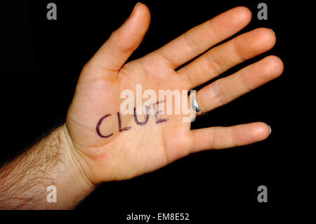 Clue written on the palm of a hand photographed against a black background. Stock Photo