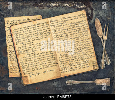 Antique silverware on rustic metal background. Vintage handwritten recipe book. Retro style toned picture Stock Photo