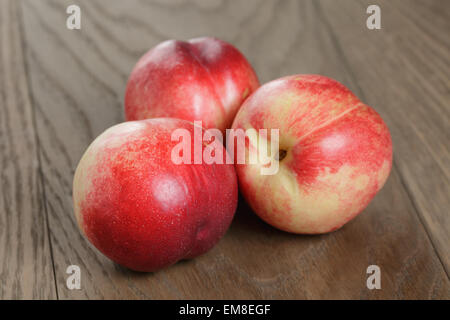 three nectarines on old wood oak table, rustic Stock Photo