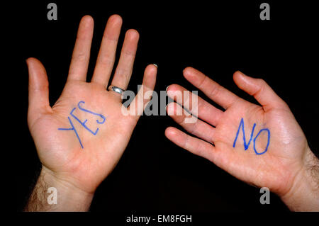 Two white hands with the words 'yes' and 'no' written on them against a black background. Stock Photo