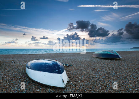 Wooden boats on a shingle beach at sunset Stock Photo