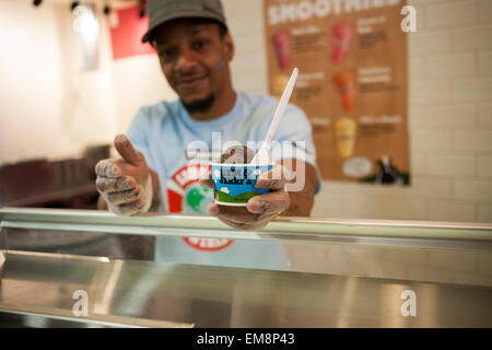 A counterperson gives away a cup of Chocolate Therapy ice cream in the Ben & Jerry's ice cream store in Times Square in New York on Tuesday, April 14, 2015 during their annual free cone day. The company celebrates its birthday by giving away thousands of free cones, this year to celebrate the 37th year that they have been in business. (© Richard B. Levine) Stock Photo