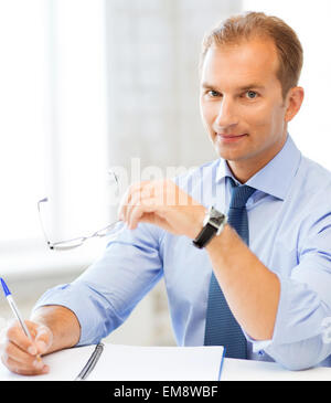 businessman with spectacles writing in notebook Stock Photo