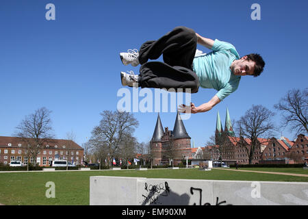 Luebeck, Germany. 15th Apr, 2015. Nils Marckwardt trains the sport 'parcours' and performs a 'free running jump' with a flip at spring temperatures and bright sunshine in Luebeck, Germany, 15 April 2015. The Holsten gate lies in the background. Photo: BODO MARKS/dpa/Alamy Live News Stock Photo