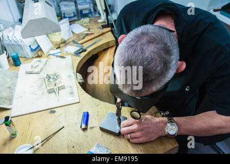 Jewellery craftsman using hammer on workbench Stock Photo