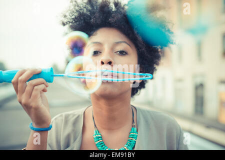 Portrait of young woman blowing bubbles with large wand Stock Photo