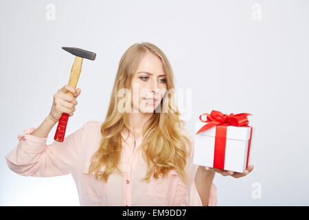 young blond woman with present box and a hammer in her hand. Stock Photo