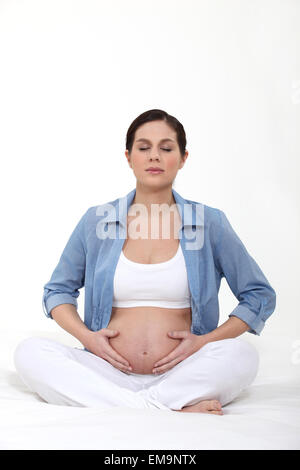 Pregnant woman practising yoga Stock Photo