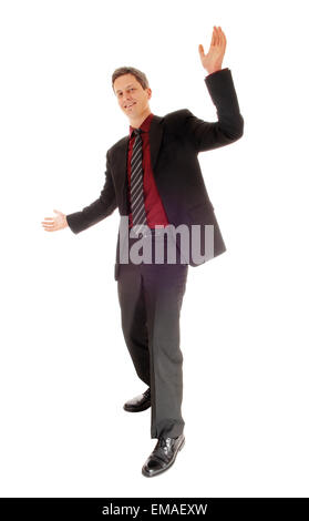 A full body picture of a dancing man in a suit and tie with his arms raised isolated for white background. Stock Photo