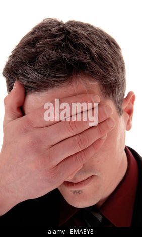 A young man in a suit and tie standing isolated for white background with one hand covering his face. Stock Photo