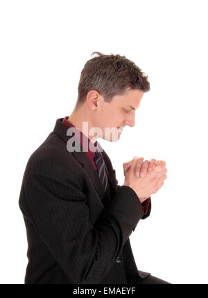 A young businessman in an suit and tie folding his hands and preying, isolated for white background. Stock Photo