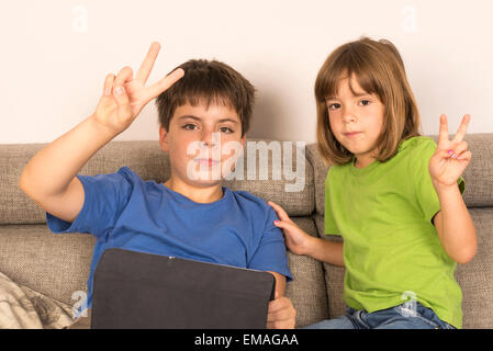 Children playing with a digital tablet on the sofa Stock Photo