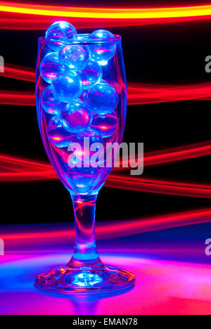 Clear Marbles in a Wine glass with blue and red light painting Stock Photo