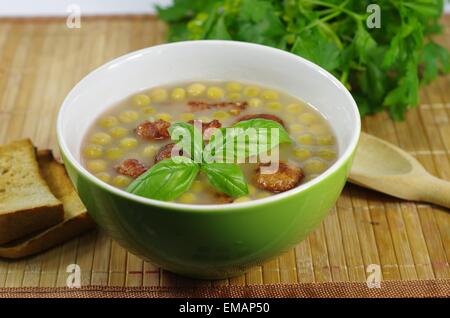 Appetizing hot pea soup with smoked meats served with slices of bread ...