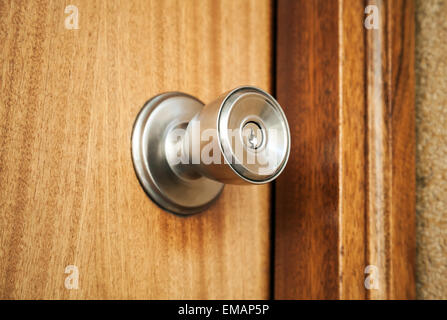 Shining metal door handle with keyhole in closed wooden door, photo with selective focus and shallow DOF Stock Photo