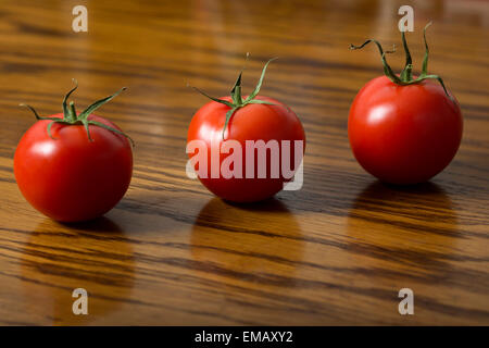 Three tomatoes on dark wooden table Stock Photo