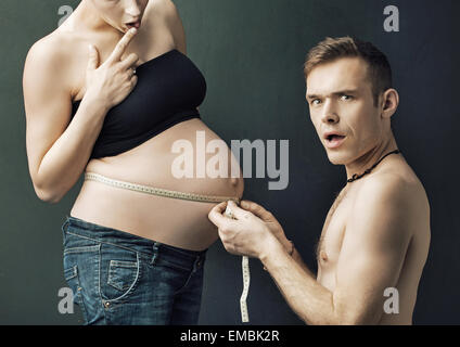 Glad parents measuring on pregnant woman's belly Stock Photo