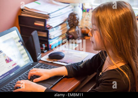 Nine year old girl playing on a laptop computer at a desk in Issaquah, Washington, USA Stock Photo