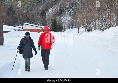 Man and woman walking along the snowy road in Sounkyo Stock Photo