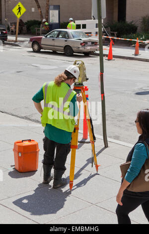 Worker using land survey station on tripod - USA Stock Photo
