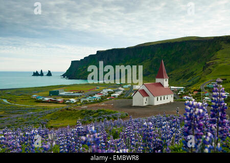 View over Vik (vik i myrdal) with its church and the reynisdrangar (basalt sea stacks) at dawn, South Iceland Stock Photo