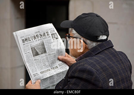 A Chinese American senior citizen reading a Chinese newspaper in Columbus Park in Chinatown, Manhattan, New York City. Stock Photo
