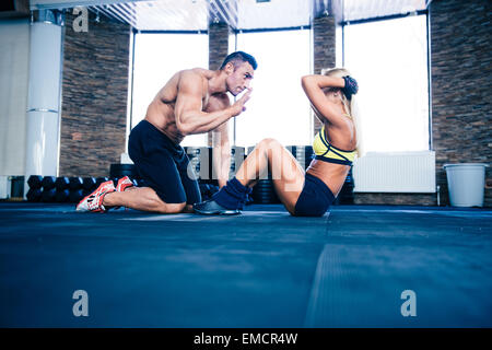 Woman doing abs exercise with coach in crossfit gym Stock Photo