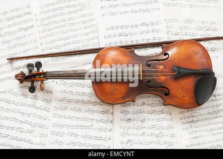 Old violin with bow on the background notes. Stock Photo