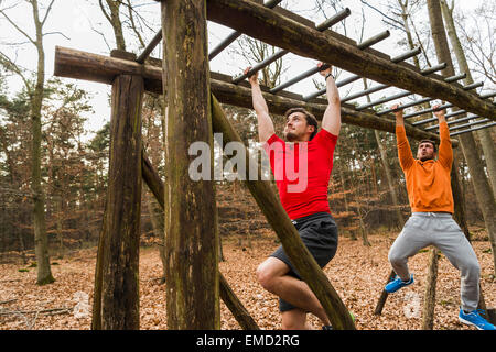 Two young men brachiating on climbing frame Stock Photo