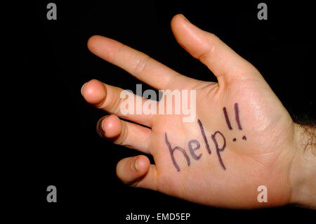 Help!! written on a white man's hand photographed against a black background. Stock Photo