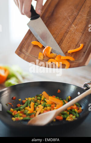 close up of male hand adding peppers to wok Stock Photo