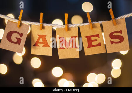 The word GAMES printed on clothespin clipped cards in front of defocused glowing lights. Stock Photo