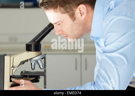Scientist Looking Through Microscope In Laboratory Stock Photo