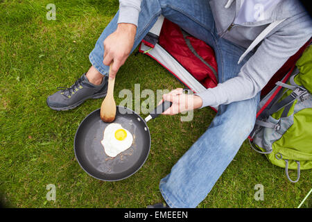 Man On Camping Holiday Frying Egg In Pan Stock Photo